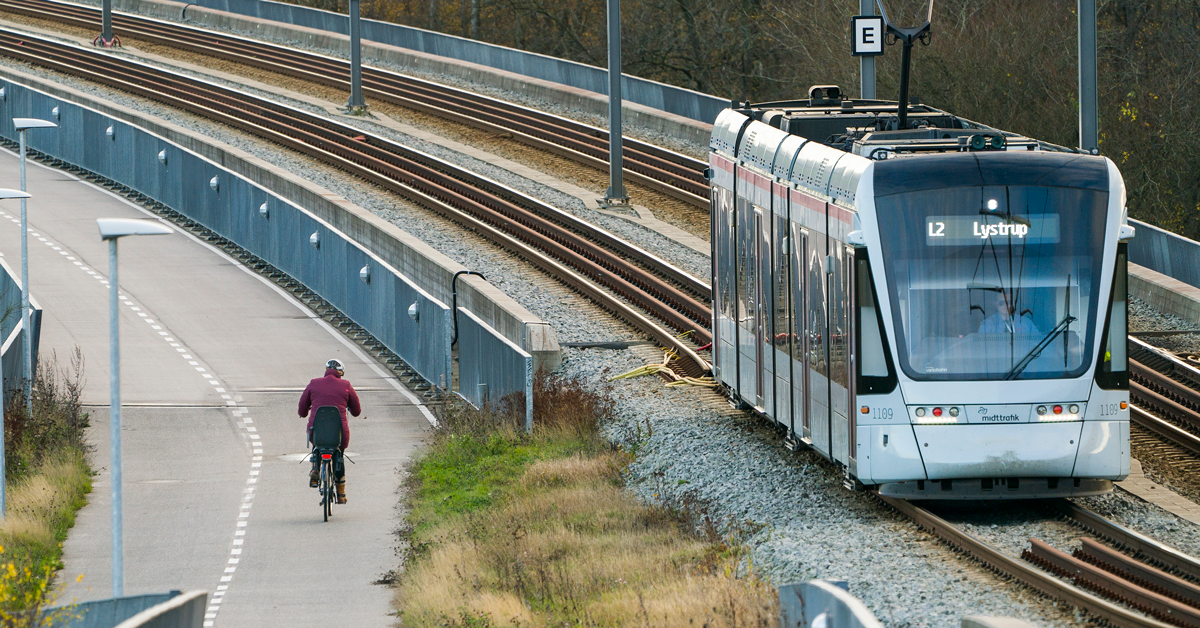 Et letbanetog og en cykelrytter passerer hinanden.