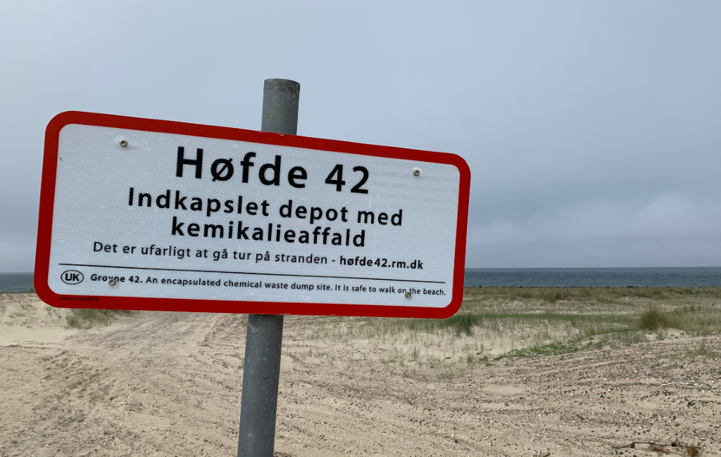Skilt på stranden ved Høfde 42 med havet i baggrunden.